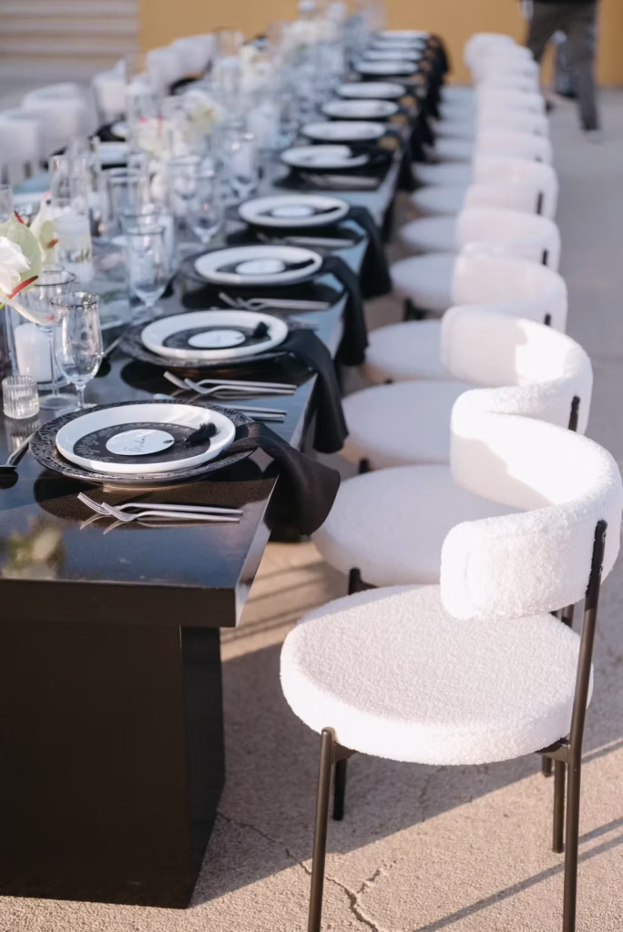 Long wedding reception table with black accents and white chairs. Cabo Wedding Planner.